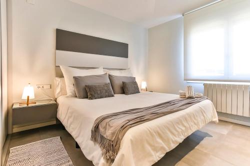 a bedroom with a large white bed with a large window at MAGNÍFICO APARTAMENTO - primera línea de mar in Calafell