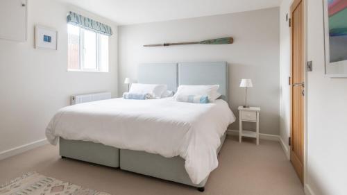 a white bedroom with a large bed and a window at Treetops in Salcombe