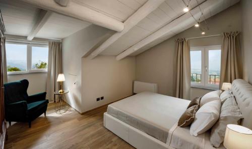 Villa Gremì - Monforte d'Alba في مونفورتي دالبا: غرفة نوم بسرير ابيض كبير وكرسي