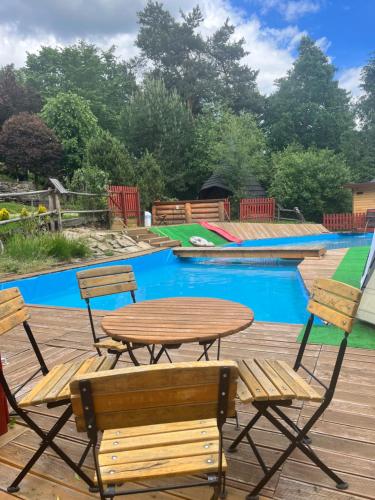 una mesa de madera y sillas junto a una piscina en Zajazd Cicha Woda, en Maniowy