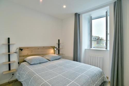 un dormitorio con una cama y una ventana en L'Amanyn - Appartement proche plage, en Dinard