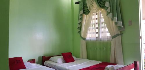 2 Betten in einem grünen Zimmer mit Fenster in der Unterkunft Sea Apartment-Pinca in Manila