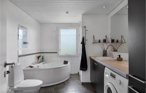 ein Badezimmer mit einer Badewanne, einem WC und einem Waschbecken in der Unterkunft Cozy Home In Lkken With Kitchen in Løkken