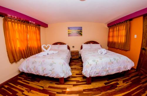 a bedroom with two beds with white sheets at Intitambo Hotel in Ollantaytambo