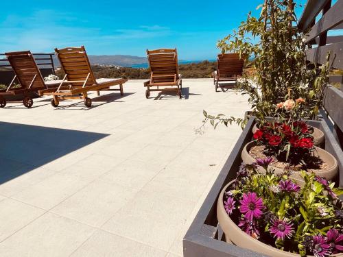 a patio with lawn chairs and flowers in pots at Phaedra House For Relaxing Holidays Near Platanias in Vlakheronítissa