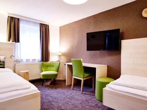 a hotel room with two beds and a desk and a tv at Das Grüne Hotel zur Post - 100 % BIO in Salzburg