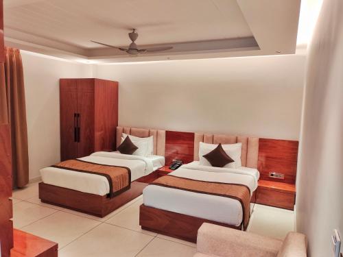 een hotelkamer met 2 bedden en een bank bij HOTEL SUNCITY PALACE in Katihār