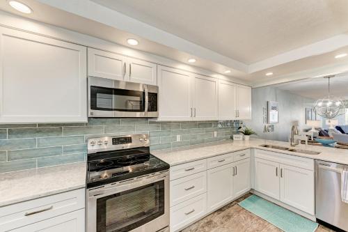 a kitchen with white cabinets and a stove top oven at Resting Beach Place managed by Beach Retreats in Holmes Beach