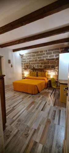a bedroom with a yellow bed and a brick wall at Kabula in Olbia