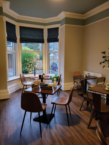 a dining room with tables and chairs and windows at The Garden Rooms at Tannery House in Bakewell