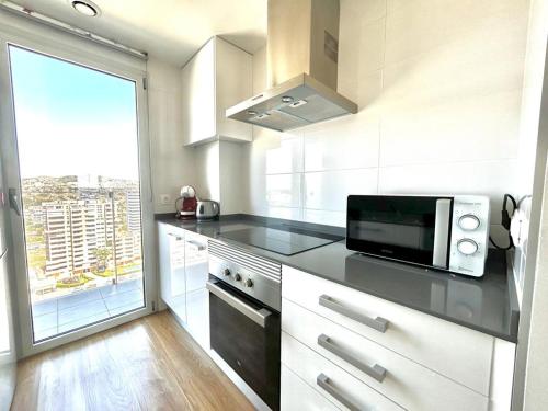 a white kitchen with a microwave and a window at Mirador de Calpe. Apartment with panoramic views. in Calpe
