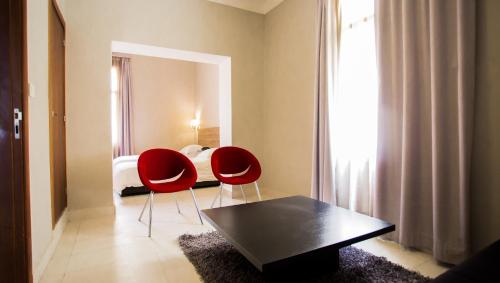 Hôtel Olympic في فاس: غرفة بها كرسيين حمر وسرير