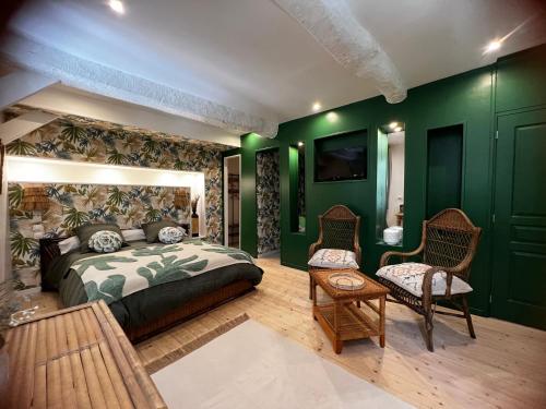 Saint-Féliu-dʼAvallにあるLe Cèdre 1830 Maison d'hôtes de charmeの緑の壁のベッドルーム(ベッド、椅子付)