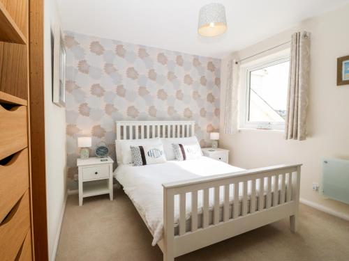 a bedroom with a white bed and a window at Sea Breeze in Y Felinheli