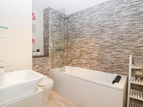 a bathroom with a tub and a toilet and a sink at Sea Breeze in Y Felinheli