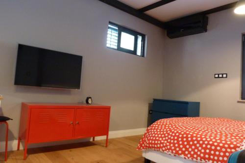 um quarto com uma cómoda vermelha e uma televisão de ecrã plano em We Collect Umbrellas em Split