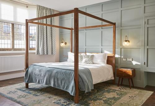 a bedroom with a canopy bed with white pillows at The Old New Inn in Bourton on the Water