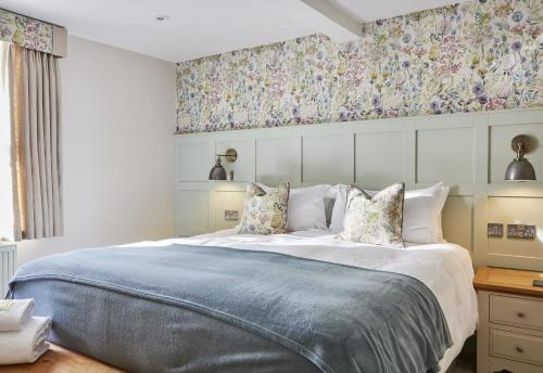 a bedroom with a large bed with floral wallpaper at The Old New Inn in Bourton on the Water