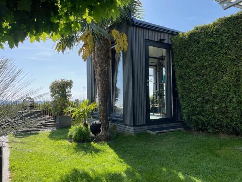 a black house with a palm tree in the yard at TINY-HOUSE mit Alpen- Stadt- und Poolblick , WLAN in Passau