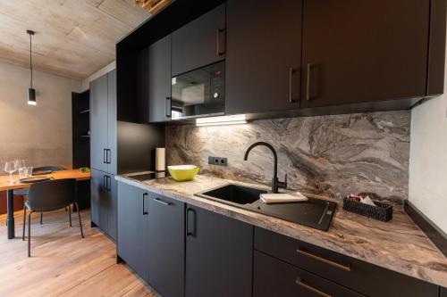 a kitchen with black cabinets and a sink at Living Rain in Rain