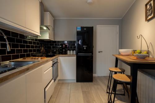 La cuisine est équipée de placards blancs et d'un réfrigérateur noir. dans l'établissement Gorgeous House with BBQ Patio, à Great Yarmouth