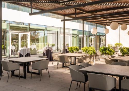 un restaurant avec des tables, des chaises et des fenêtres dans l'établissement Hotel SB BCN Events 4* Sup, à Castelldefels