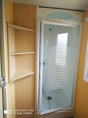 une douche avec une porte vitrée dans une salle de bain dans l'établissement Mobil home au bord du lac, à Nages