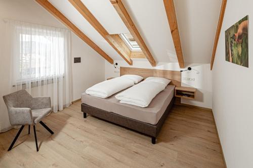 a bedroom with a bed and a chair at Prälatenhof Wine & Apartments in Caldaro