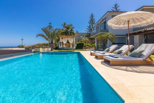 a swimming pool with lounge chairs and an umbrella at Villa Ioulia Gouves in Gouves