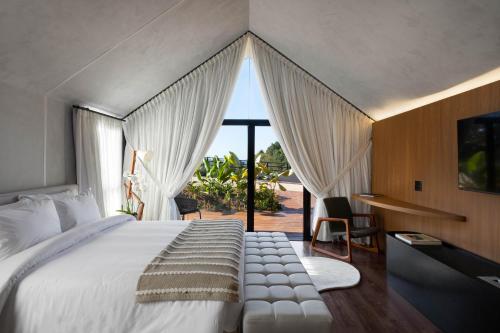 a bedroom with a large white bed with a window at NÖR Hotel & SPA in São Roque