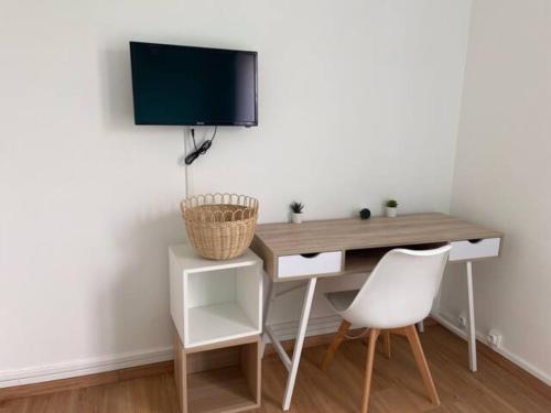 escritorio con silla blanca y TV en la pared en Chambre dans appartement lumineux, en Mont-Saint-Aignan