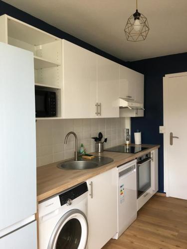 una cocina con armarios blancos y una lavadora. en Chambre dans appartement lumineux, en Mont-Saint-Aignan
