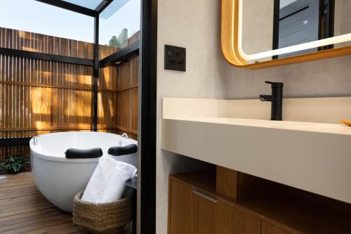 a bathroom with a bath tub and a sink at NÖR Hotel & SPA in São Roque