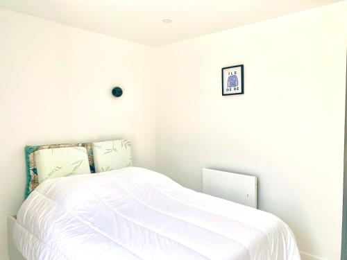 a white bedroom with a bed with white sheets at CAPUCINE Jolie maison proche Plage in La Couarde-sur-Mer