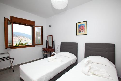 two beds in a room with a window at Finikas Apartments in Skopelos Town