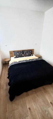 a black bed in a white room with a wooden floor at Duplex Holiday Apartment in Škofljica