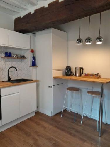 une cuisine avec des armoires blanches et des tabourets de bar dans l'établissement Le cité d'or, à Dijon