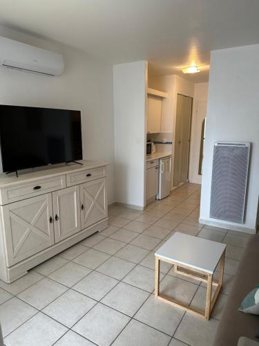 un salon avec une télévision à écran plat sur une armoire dans l'établissement Vue sur le port, au Cap d'Agde