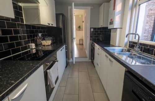 a kitchen with black and white counter tops at Cozy House with Modern Garden in Great Yarmouth