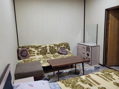 a room with a couch and a table and a dresser at UZUMZOR HOUSE in Aktepa-Chigatay
