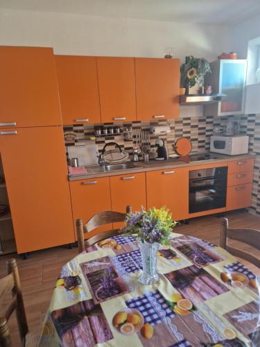 a kitchen with orange cabinets and a table with flowers at Vera Apartment in Rab