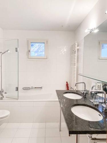a white bathroom with two sinks and a shower at 4 1/2 Room Maisonette Apartment with great views in Sils Maria