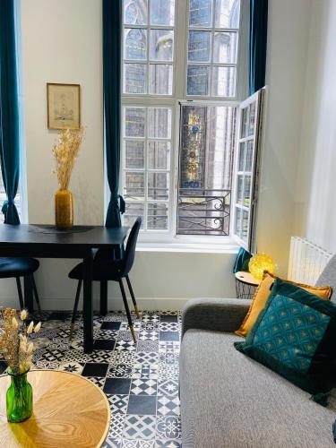 un salon avec un canapé, une table et une fenêtre dans l'établissement Le Rituel St Maclou, hyper centre vue sur église, à Rouen
