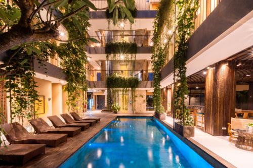 a swimming pool in a building with plants at Tanaga CoLiving in Seminyak