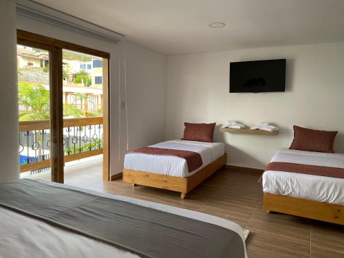 a hotel room with two beds and a balcony at Hotel Gran Plaza San Agustin in San Agustín