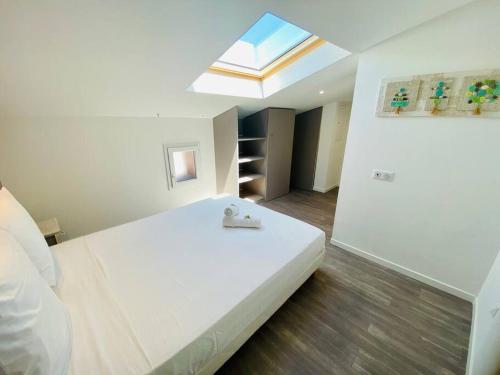 a bedroom with a large white bed with a skylight at ''L'Amandier'' Cosy T2 en coeur de ville, climatisé in Sète