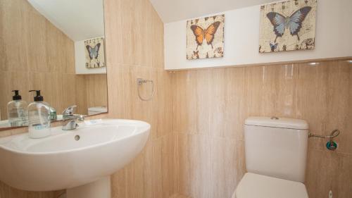 baño con lavabo y aseo y mariposas en la pared en La Borboleta 8, en Manilva
