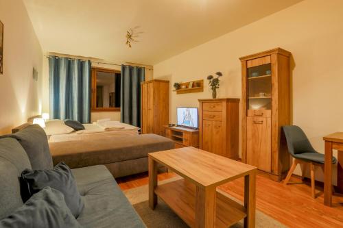 a bedroom with a bed and a couch and a table at Apartmány Fatrapark 1 s WELLNESSOM Hrabovská dolina in Ružomberok