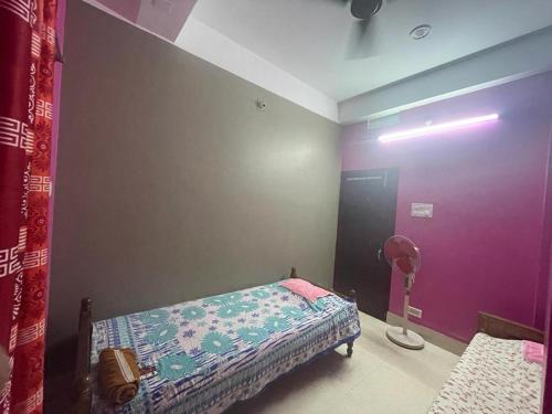 a bedroom with a bed and a purple wall at Veda Home's in Agartala