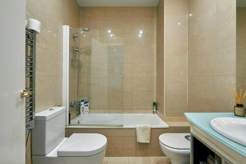 uma casa de banho com uma banheira, um WC e um lavatório. em Quiet Luxury 2-bed apartment for couples & families em Barcelona